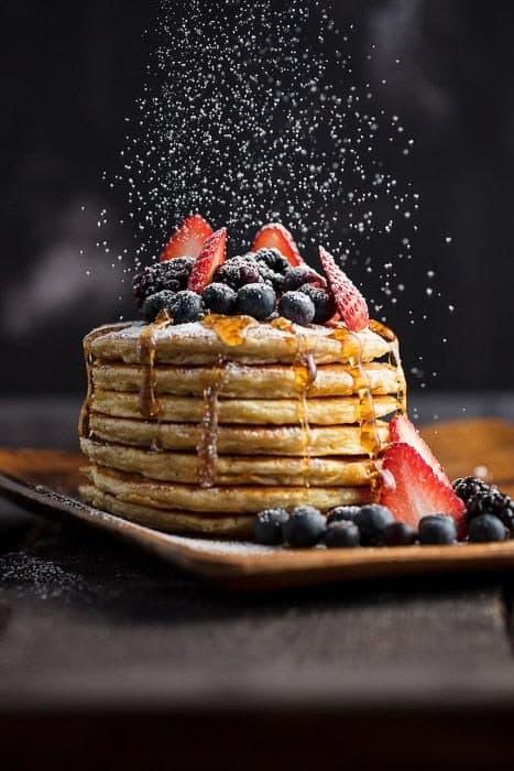 Pancakes topped with berries beneath a dusting of sugar.