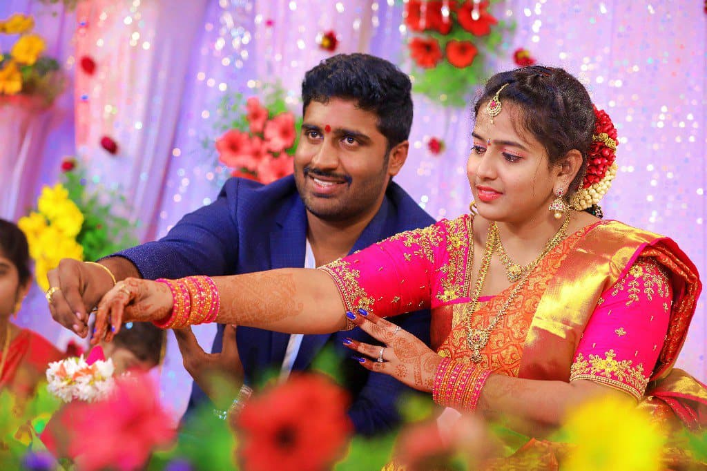 A bride and groom exchanging flowers during a wedding ceremony, framed by floral decoration.