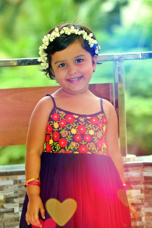 A young girl wearing a flower crown standing outdoors.