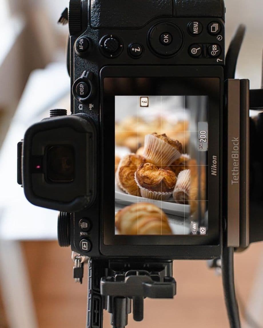 A camera on a tripod framing muffins during a food photography shoot.