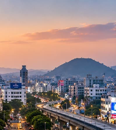 Vijayawada at dusk — the city skyline and the lit flyover beneath the hills.