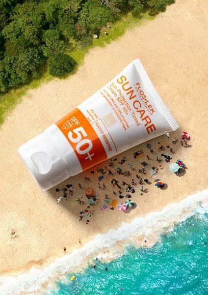A sunscreen tube laid across an aerial view of a beach.