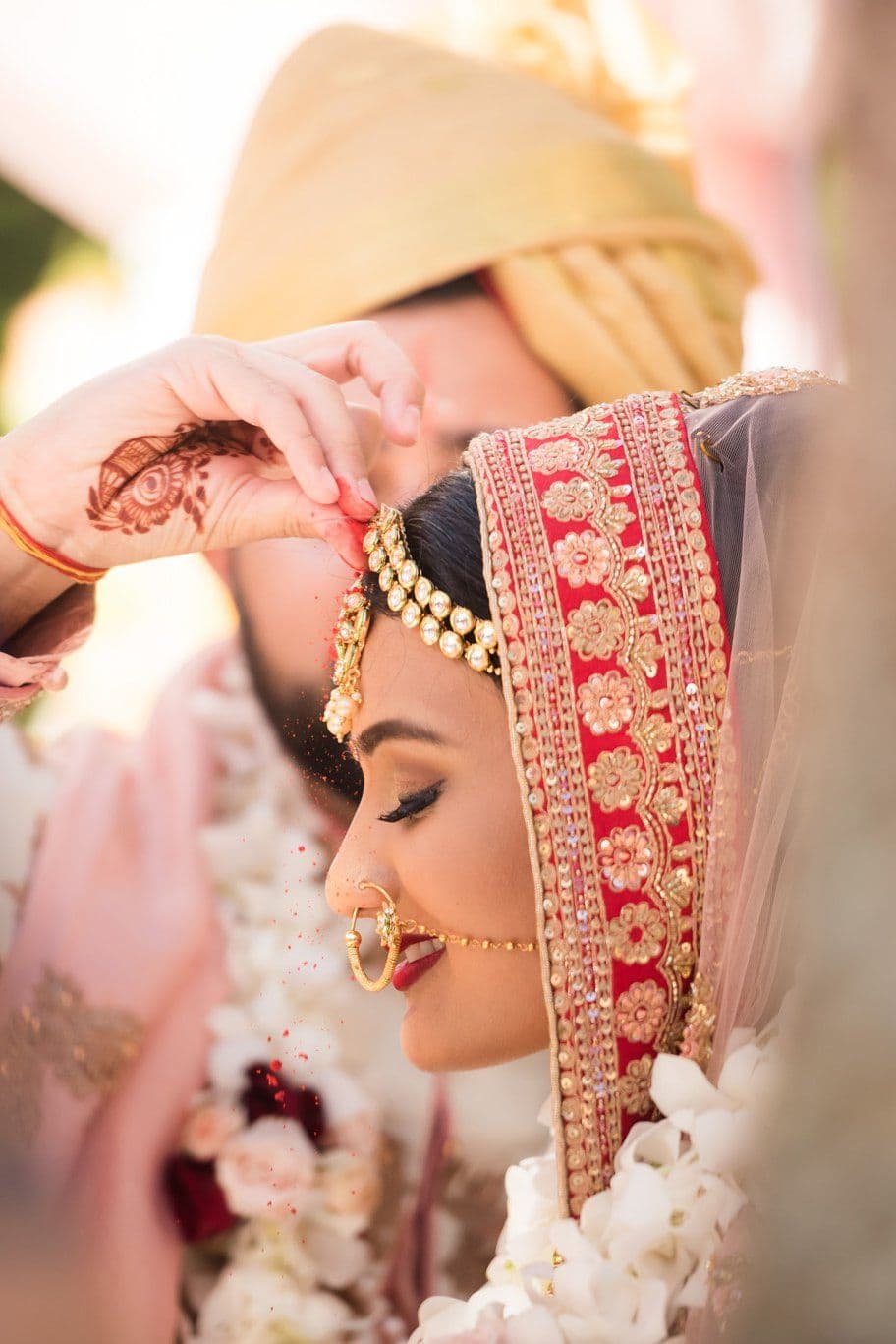 A bride in red and gold wedding attire during a Hindu wedding ritual.